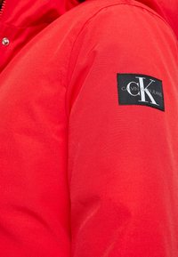 Rode outerwear met een gladde textuur en een logo patch van Calvin Klein Jeans op de linker mouw. Rits sluiting aan de voorkant.