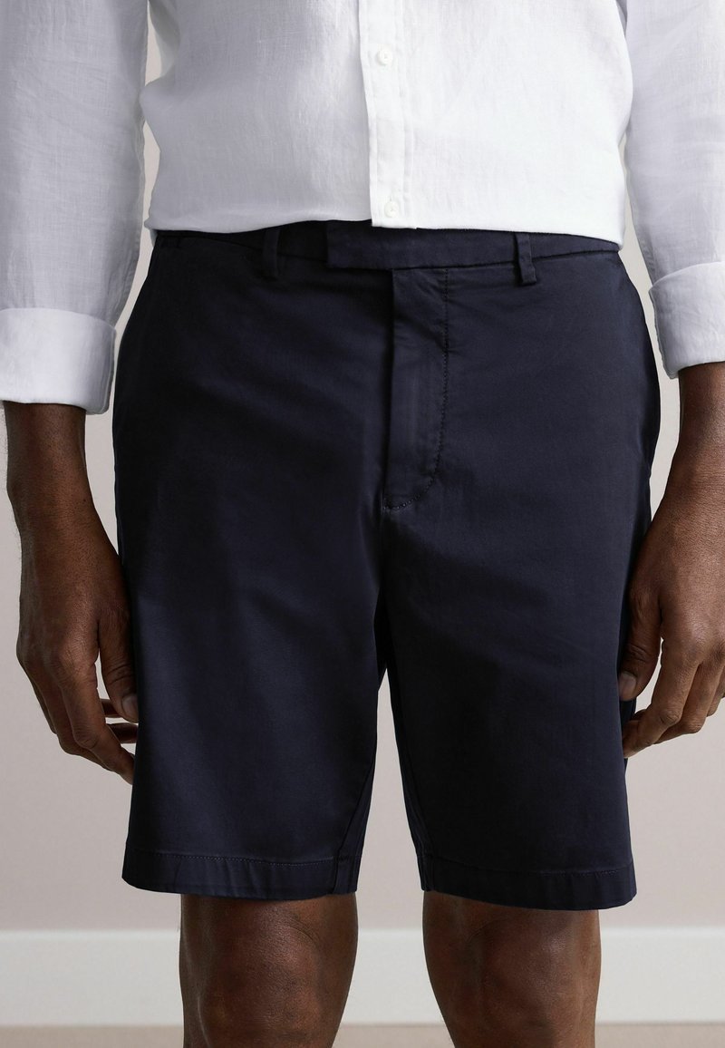 Navyblaue Shorts mit geradem Schnitt, aus glattem Stoff. Verfügt über einen Bund mit Gürtelschlaufen und einen Reißverschluss vorne.