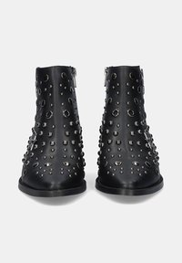Botas de cuero negro hasta el tobillo con acentos de tachuelas plateadas y recortes circulares. Presentan un diseño elegante, puntera redondeada y cremalleras en la parte trasera.