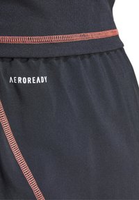 Pantaloni sportivi neri con etichetta AEROREADY, cuciture arancioni a contrasto lungo le cuciture e una texture del tessuto liscia e traspirante.