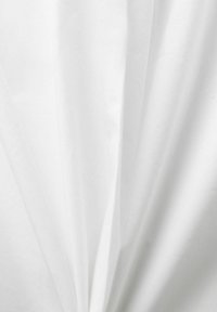 Tissu blanc avec des plis doux et des ombres délicates créant une texture lisse et fluide.