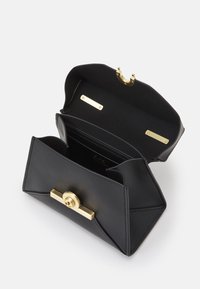 Borsa in pelle nera con chiusura dorata aperta che mostra l'interno con scomparti per carte e lati strutturati su sfondo bianco.