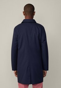 Marineblauer, knielanger Mantel mit klassischem Kragen, langen Ärmeln und einer Rückenbelüftung. Glattes Material mit minimalistischem Design.