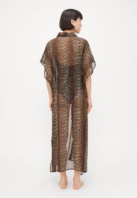 Prozirni kimono-stil bundič s leopard printom, s ovratnikom, kratkim rukavima i dugim, otvorenim prednjim dijelom, s kombinacijom smeših i crnih nijansi.