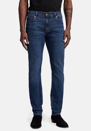 Jean en denim bleu foncé avec une coupe droite, design à cinq poches, détails de couture subtils et fermeture à bouton à la taille.