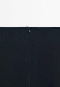 Musta farkkukangasta tyynynpäällinen, jossa on keskellä vetoketjukiinnitys. Pinta on teksturoidut ja saumat suorat, mikä luo siistin lopputuloksen.