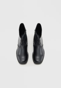 Μαύρα δερμάτινα μποτάκια αστραγάλου με κομψή, λεία υφή, που διαθέτουν διακριτικό σχέδιο και φερμουάρ στο πλάι. Τετράγωνη μύτη και χαμηλό τακούνι.