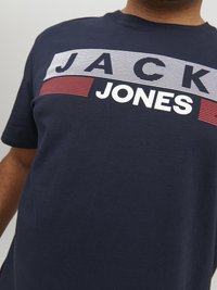 Marineblaues Baumwoll-T-Shirt mit horizontalen Streifen, auf denen "JACK" in Weiß und "JONES" in Rot geschrieben steht. Rundhalsausschnitt, kurze Ärmel, glatte Textur.