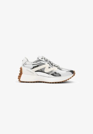 Baskets métalliques argentées avec des accents blancs, semelle en gomme, fermeture à lacets et marquage "Steve Madden" sur le côté.