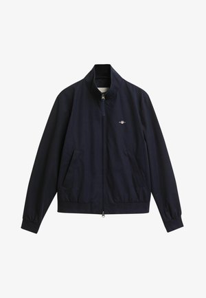 Giacca zip blu navy con colletto alto, tasche frontali, polsini elastici e un piccolo logo sul petto. Realizzata in tessuto liscio.