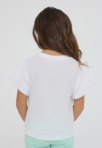 Camicia bianca a maniche corte con maniche arricciate morbide, dotata di scollo tondo e una texture di cotone liscia.