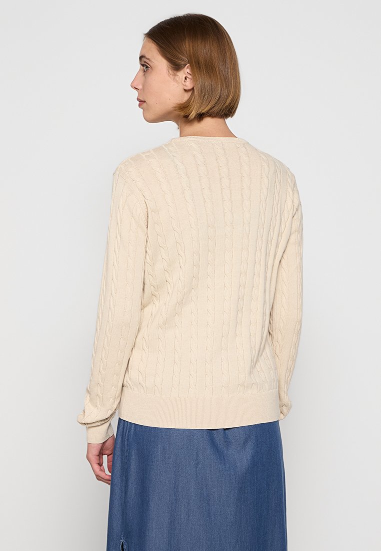 Beige Kabelstrickpullover mit rundem Ausschnitt, langen Ärmeln sowie zweifarbigen Bündchen und Saum. Die Rückansicht zeigt ein strukturiertes Muster und weichen Stoff.