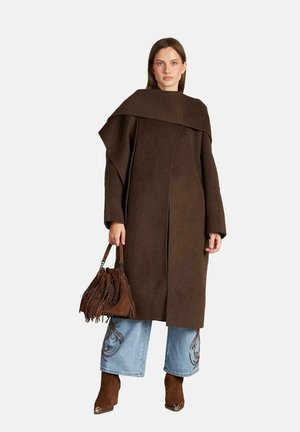 Abrigo de lana marrón con un cuello oversize y costuras laterales. Combinado con pantalones vaqueros de pierna ancha en azul claro con bordados y botas de tacón marrones.