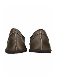 Une paire de chaussons en cuir marron à enfiler avec des coutures blanches visibles et des semelles noires, présentée de face sur un fond blanc.