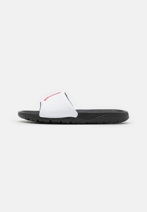 Sort slidssandal med hvid rem med rødt Nike-logo, vist fra siden på en almindelig lys baggrund.