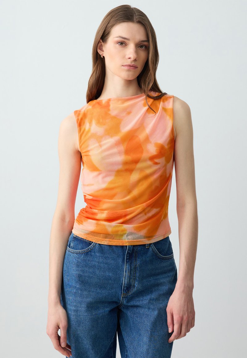 Strakke, mouwloze top in een verloop van oranje en roze bloemmotieven. Gemaakt van een lichtgewicht, textuurstof met geplooide details aan de zijkant.