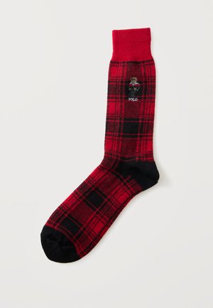 Chaussette à carreaux rouge et noir avec bout et talon noirs, affichant un petit ours brodé portant une veste rouge et le mot "POLO" en dessous.