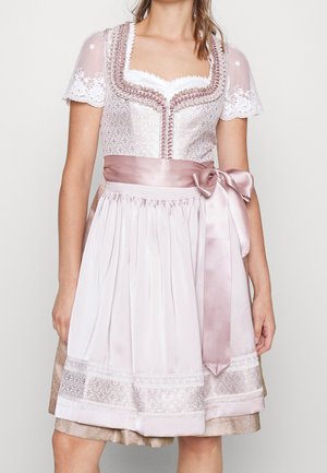 Femme portant une robe traditionnelle rose pâle avec des manches courtes en dentelle, un corsage brodé et une ceinture en satin nouée en un nœud sur le côté droit.