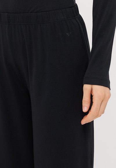 Melnas jogger bikses, kas izgatavotas no mīksta auduma, ar elastīgu jostas vietu, ar mazu logo sānos un brīvu piegriezumu.