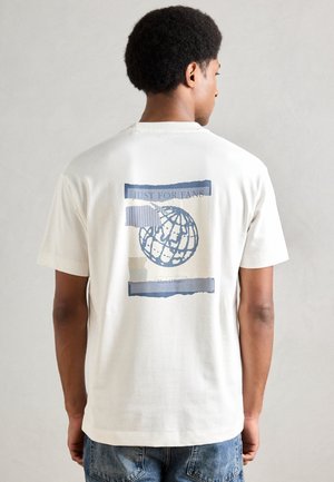 T-shirt de algodão creme de manga curta com gráfico de globo azul e texto nas costas. Apresenta um corte relaxado e decote redondo.