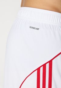 Hvide træningsshorts med røde accentstriber og et "AEROREADY"-logo på linningen. Materialet ser glat og let ud.