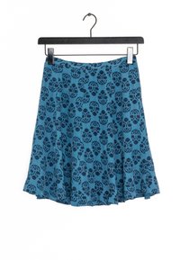 Uppklippt kjol i livlig blå färg med mörk blommönster, tillverkad av mjukt tyg. Har en enkel midjeband och hänger från en svart galge.