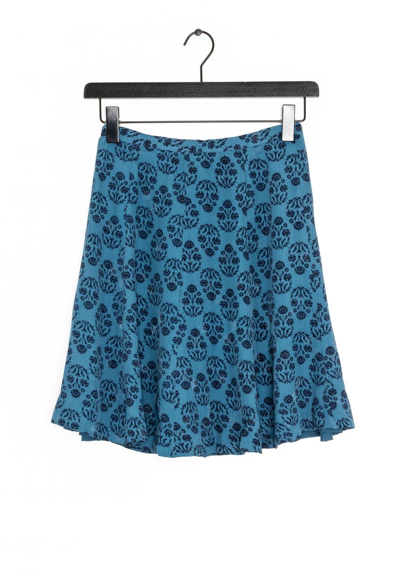 Uppklippt kjol i livlig blå färg med mörk blommönster, tillverkad av mjukt tyg. Har en enkel midjeband och hänger från en svart galge.