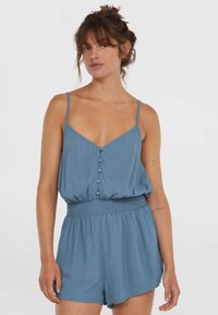 Blue romper with thin straps, v-neckline, button details down the front, and smocked waist, featuring a loose, comfortable fit.