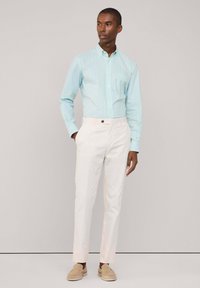 Lichtblauw en wit gestreepte button-up overhemd gecombineerd met crèmekleurige broek, met een slim fit en een soepele textuur.