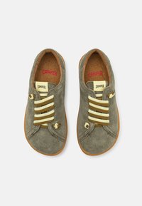 Scarpe in suede verde con lacci gialli e marroni, dettagli cuciti e suola in gomma marrone chiaro. L'interno presenta una soletta in sughero.