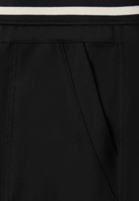 Schwarzer Stoff mit glatter Textur, mit einem plissierten Design und einem kontrastierenden weißen Streifen am elastischen Bund.