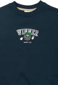 Felpa navy con scollatura rotonda, scritta "WINNER" e grafica giocosa con berretto verde e motivo a scacchi. Tessuto in cotone.