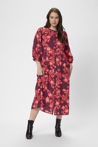Robe longue à fleurs en bordeaux et rose, avec des manches ballon et des boutons sur le devant. Portée avec des bottines noires. Texture douce.