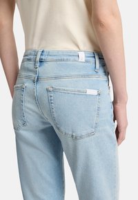 Jasnoniebieskie dżinsy o prostym kroju, z tylnymi kieszeniami i prostym wykończeniem pasa. Miękka tekstura z lekko wyblakłym wyglądem.
