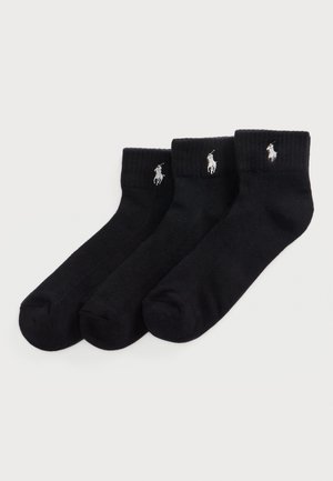 Chaussettes noires unies par lot de trois. Fabriquées en matière douce avec des bords côtelés. Présentent un petit logo brodé près du haut.