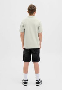 Ljust grå pikétröja med kort ärm, i kombination med rullade svarta denimshorts. Vita strumpor och svarta sneakers kompletterar outfiten.