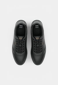 Sapatilhas de couro preto com bico perfurado, design com atacadores e acentos texturizados nas laterais. Apresenta o logo na língua e na lateral. Palmilha Ortholite®.