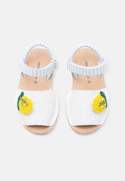 Παιδικά λευκά σανδάλια με μπλε ριγωτούς ιμάντες αστραγάλου, διακοσμημένα με κίτρινες χάντρες σε σχέδια λεμονιού στους μπροστινούς ιμάντες.