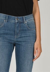 Blå denimjeans med hög midja, femfickdesign, subtil blekning och tryckknappsstängning, kompletterat med kontrasterande sömmar.