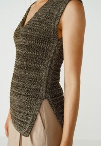 Top sans manches en maille gris métallique foncé avec motif texturé. Présente un décolleté en V profond et des fentes sur les côtés pour plus de mouvement.