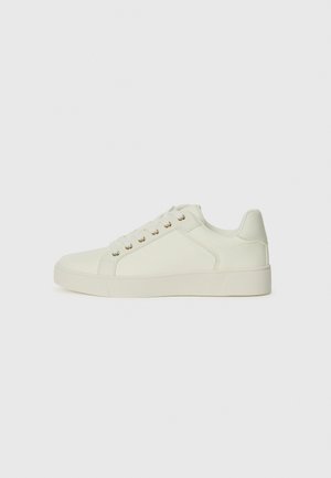 White synthetic sneakers with a smooth texture, rounded toe, and flat rubber sole. Features six eyelets and gold-toned hardware accents.