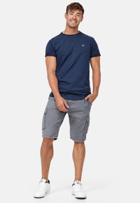 Marine crew-neck t-shirt, grå cargo-shorts med sidelommer og hvide sneakers. Afslappet tøj med en komfortabel pasform og enkelt design.