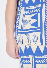 Tessuto blu e beige con un motivo che raffigura pesci e forme geometriche, caratterizzato da una texture morbida e piccole aperture laterali all'orlo.