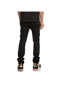 Black denim jeans with a slim fit and subtle back pocket detailing, paired with black and camouflage sneakers featuring orange accents.