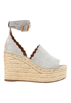Sandale compensée en daim gris clair avec bords festonnés, semelle plateforme en jute tressée et bride à la cheville avec boucle dorée.