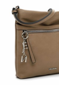 Brown leather handbag with a rounded top, a silver zipper pocket, and a charm attached. Features black piping and an embossed logo.