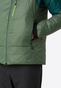 Geïsoleerde groene pufferjack met een zwarte binnenvoering, voorzien van een ritszak en contrasterende teal accenten op de schouders.