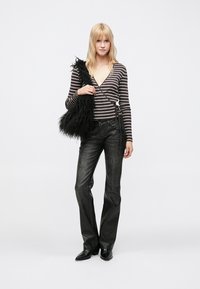 Zwart-wit gestreept top met lange mouwen, gecombineerd met donkergrijze uitlopende jeans. Model draagt een zwarte handtas met bontaccent. Eenvoudig schoeisel, algehele casual uitstraling.