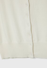 Gros plan d'un cardigan en maille couleur crème avec six boutons assortis alignés verticalement le long de l'ouverture frontale.