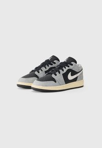 Nike lågskor i svart, grått och krämfärgat. Har övre i mocka och läder, perforerad tå och gummisula med texturerad mönster.